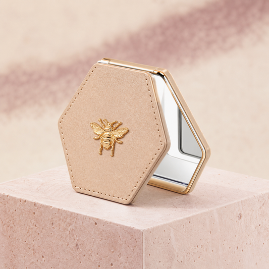 Bee Detail Folding Compact Mirror photographed on a warm ivory and blush studio backdrop
